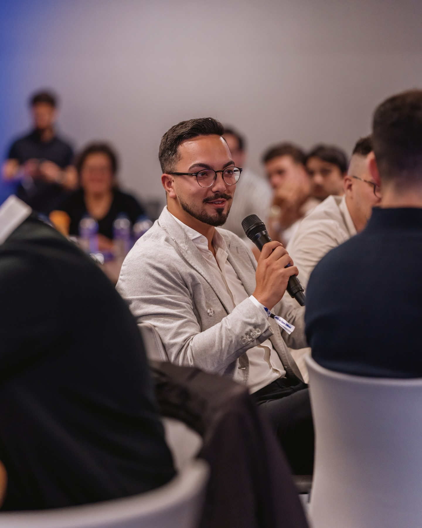 Thomas Faria com microfone numa sessão de trabalho, rodeado de participantes
